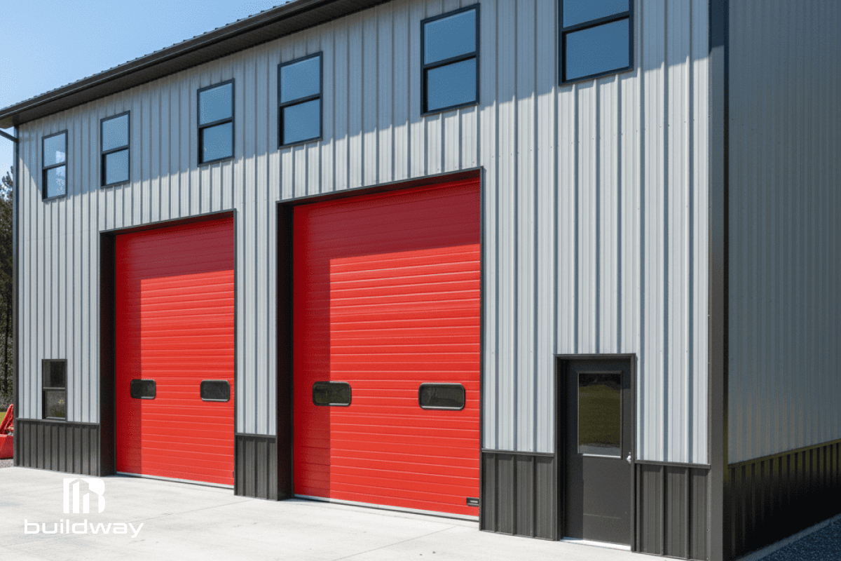 Angled exterior view of the steel workshop showing its durable construction, two red bay doors, and side entry door.