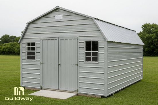 Light gray metal storage shed with double front doors and windows, placed on a grassy lawn for outdoor equipment or tool storage.