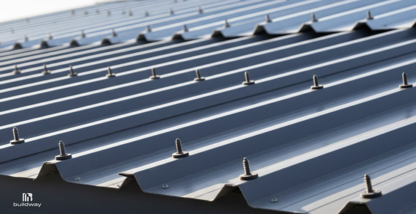 How Long Do Steel Buildings Last If You Ignore Maintenance? The Result Is Brutal 5 Close-up of an exposed fastener metal roof system, showing rows of steel panels secured with visible screws and washers aligned across the roof surface.